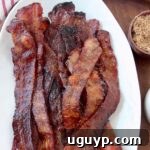 cooked slices of bacon stacked up on plate