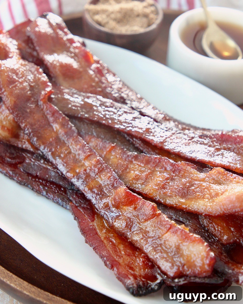 cooked candied bacon piled up on white plate