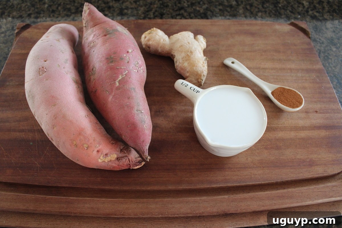 Raw sweet potatoes, coconut milk can, fresh ginger, and cinnamon on a wooden board for mashed sweet potatoes recipe.