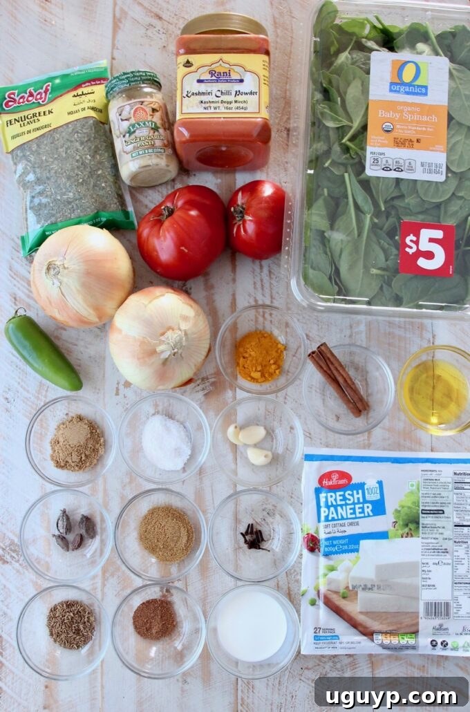 Assortment of fresh and whole spices including spinach, paneer, and various powders laid out for making Palak Paneer.