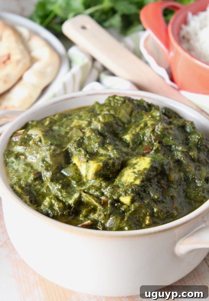 A bowl of vibrant green Palak Paneer, ready to be served with a swirl of cream on top.