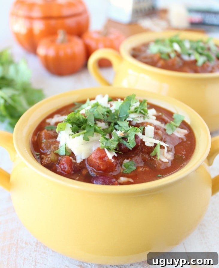 Yellow bowl filled with Pumpkin Chili garnished with melted cheese and cilantro.