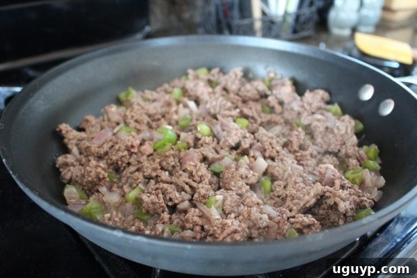 cooked ground beef with diced onions and bell peppers in a skillet