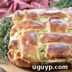 baked pot pie with weaved puff pastry crust on wood cutting board with fresh thyme