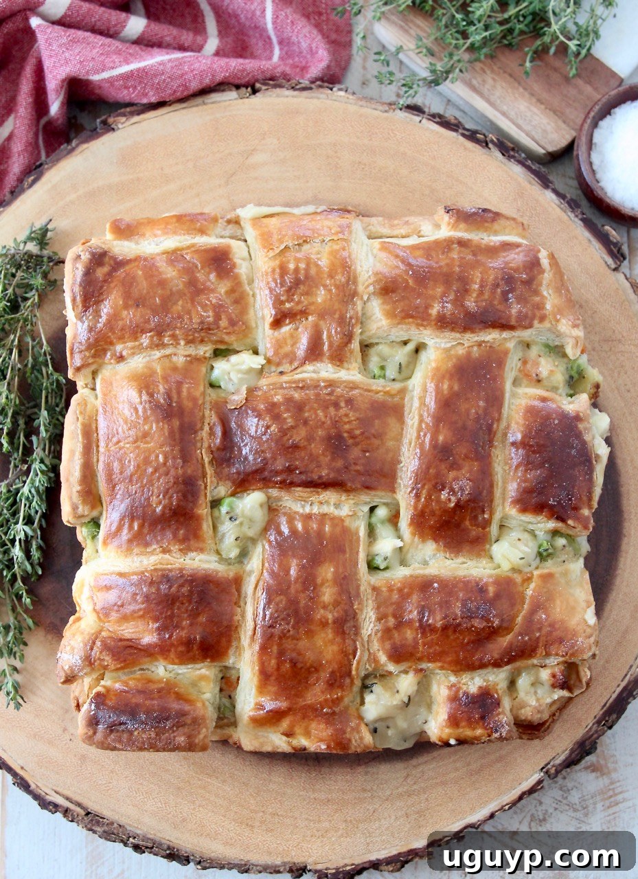 baked chicken pot pie with puff pastry crust on wood serving tray with fresh thyme