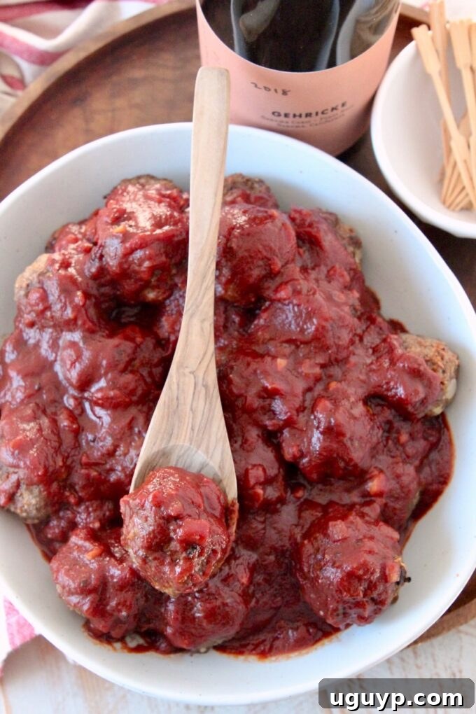 A bowl of delicious baked BBQ meatballs with a wooden spoon, ready to be served, perfect for a party or family meal.