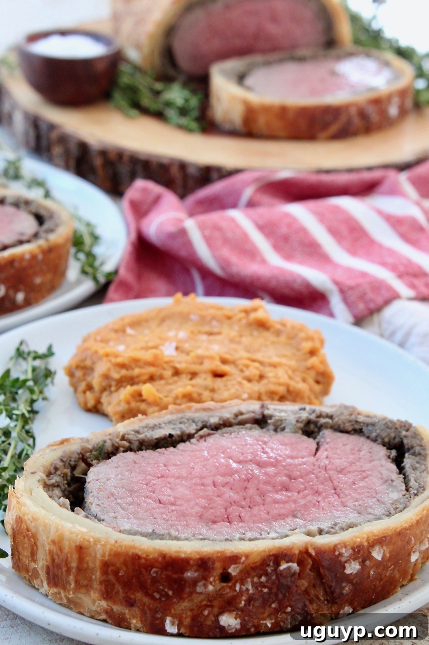 slice of cooked beef wellington on plate with mashed sweet potatoes