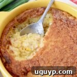 corn casserole in yellow baking dish with silver serving spoon