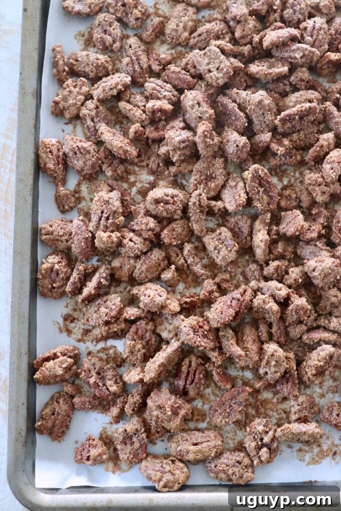 baked candied pecans spread out on baking sheet