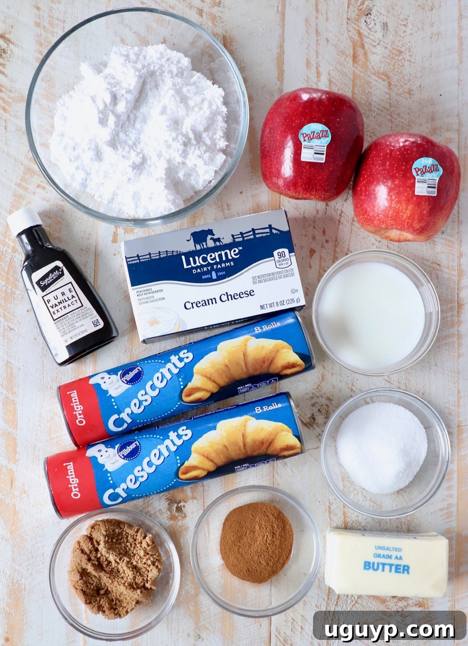 All the ingredients laid out for making a homemade apple cinnamon roll wreath, including crescent dough, apples, sugars, butter, and cream cheese.