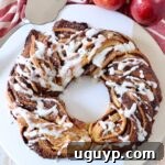 Baked cinnamon roll wreath drizzled with cream cheese frosting, a close-up for the recipe card.