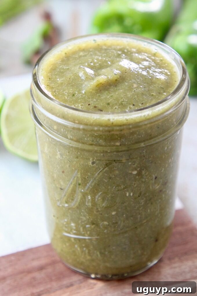 A mason jar filled with a vibrant, homemade green enchilada sauce, ready for use.