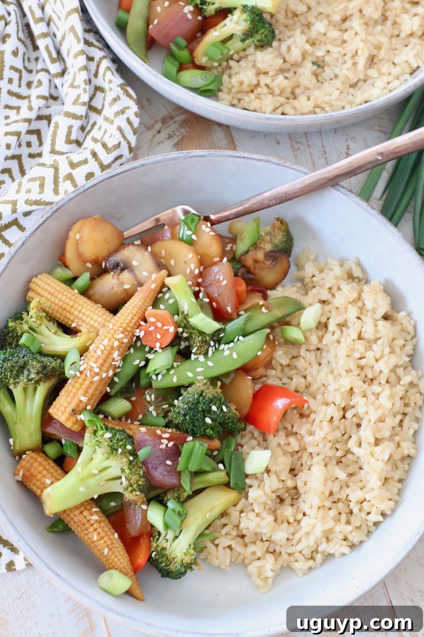 Freshly cooked vegetable stir fry in a bowl, served with brown rice and a fork, ready to be enjoyed.