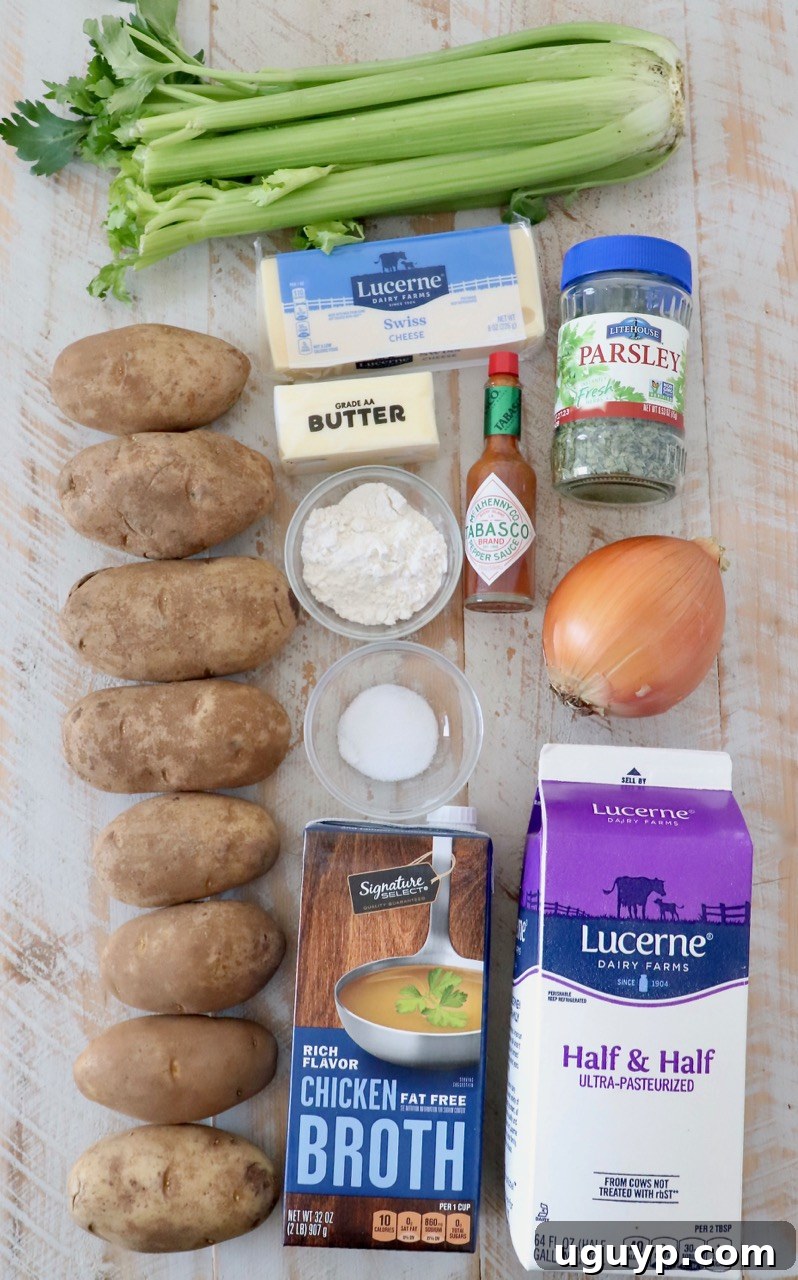 Fresh ingredients laid out on a white wooden board for making potato soup: russet potatoes, celery, onion, chicken broth, half and half, butter, flour, parsley, and Swiss cheese.