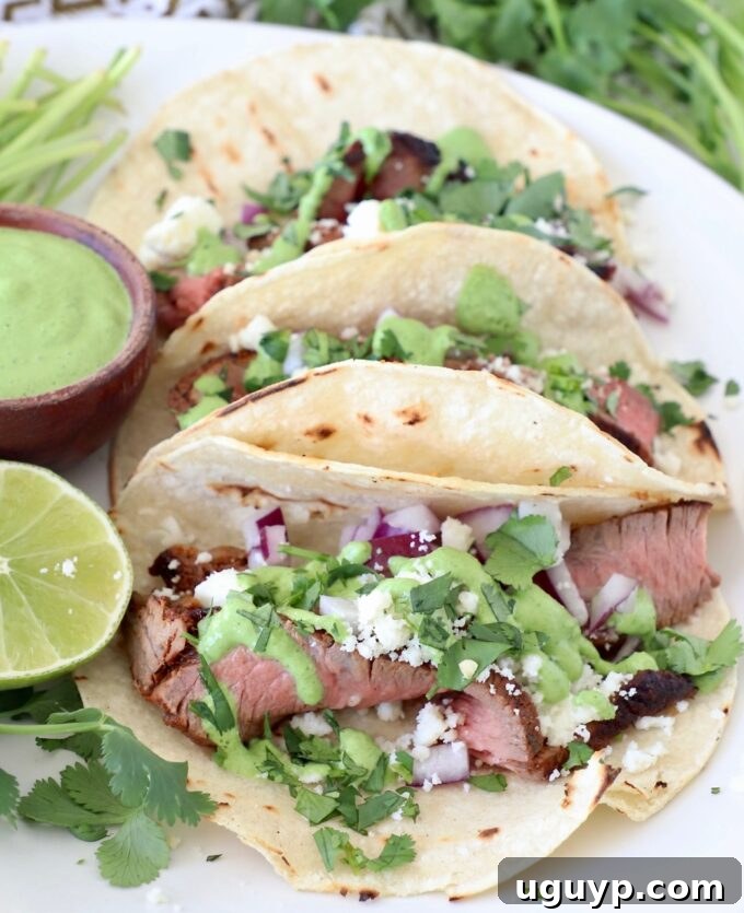 steak tacos on plate with cilantro sauce and fresh lime