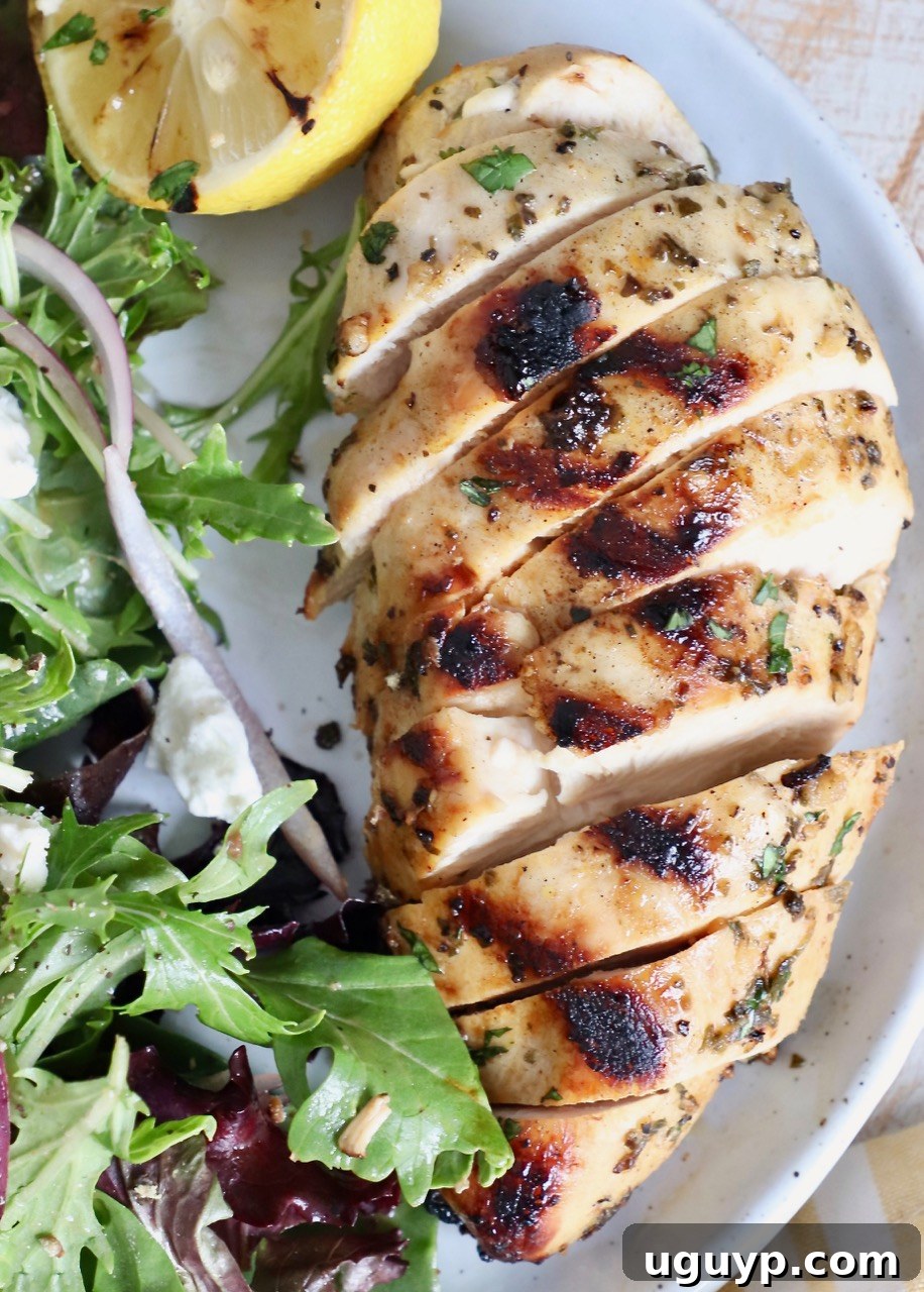 Juicy grilled Greek chicken slices served on a plate with a fresh green salad, highlighting a healthy and delicious meal option.