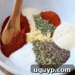 A bowl of spices and herbs, representing the easy homemade pork chop seasoning mix, with a wooden spoon.