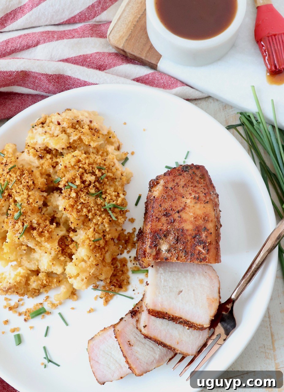 Close-up of a perfectly sliced smoked pork chop with mac and cheese, emphasizing its moist texture and ideal doneness.