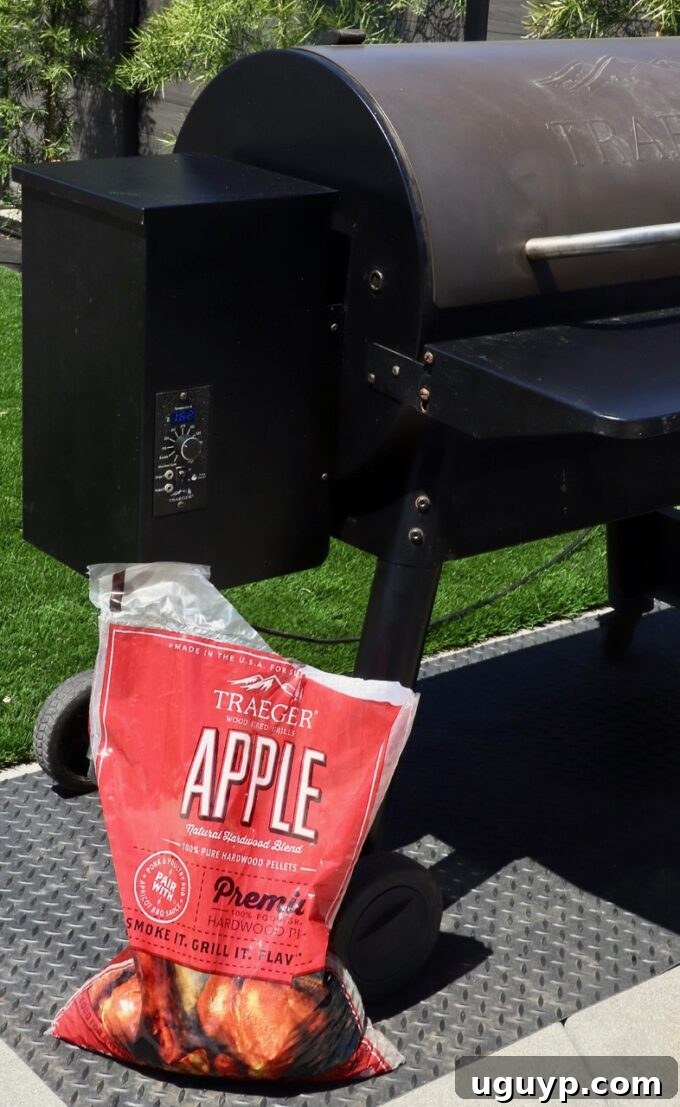 A bag of applewood pellets placed next to an outdoor smoker, indicating the choice of wood for smoking.