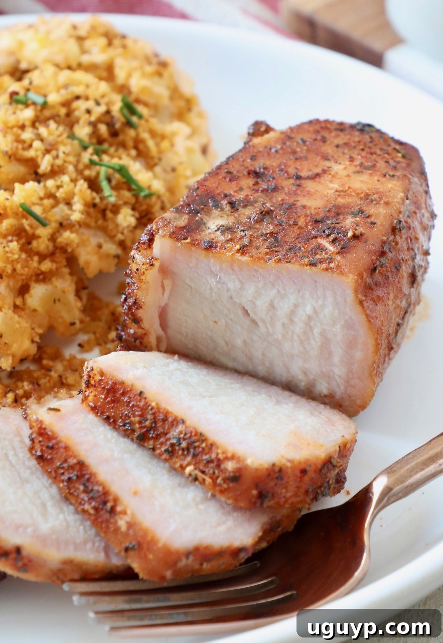 A perfectly sliced smoked pork chop served on a plate with creamy mac and cheese, highlighting the moist interior.