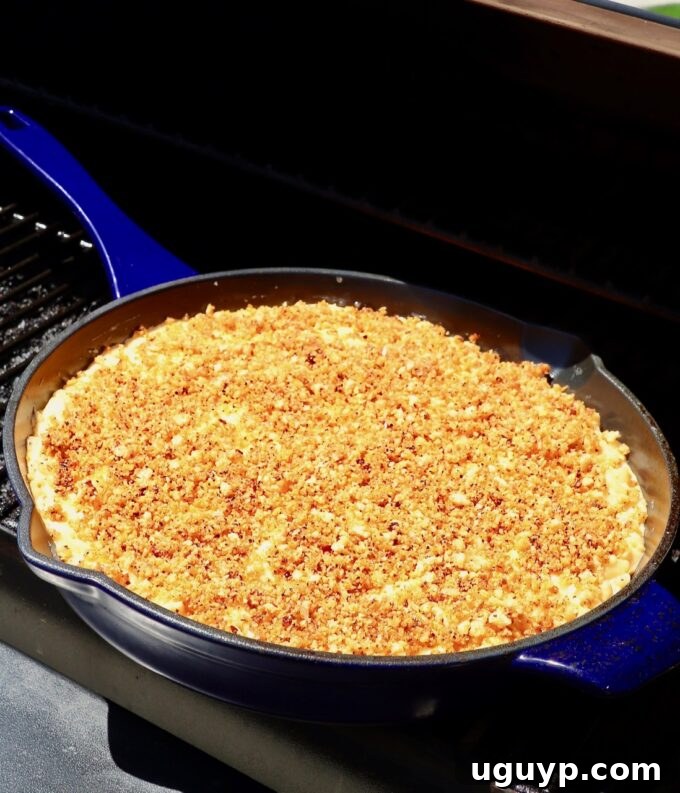 A cast iron skillet of mac and cheese placed inside a preheated smoker, ready to infuse smoky flavor.