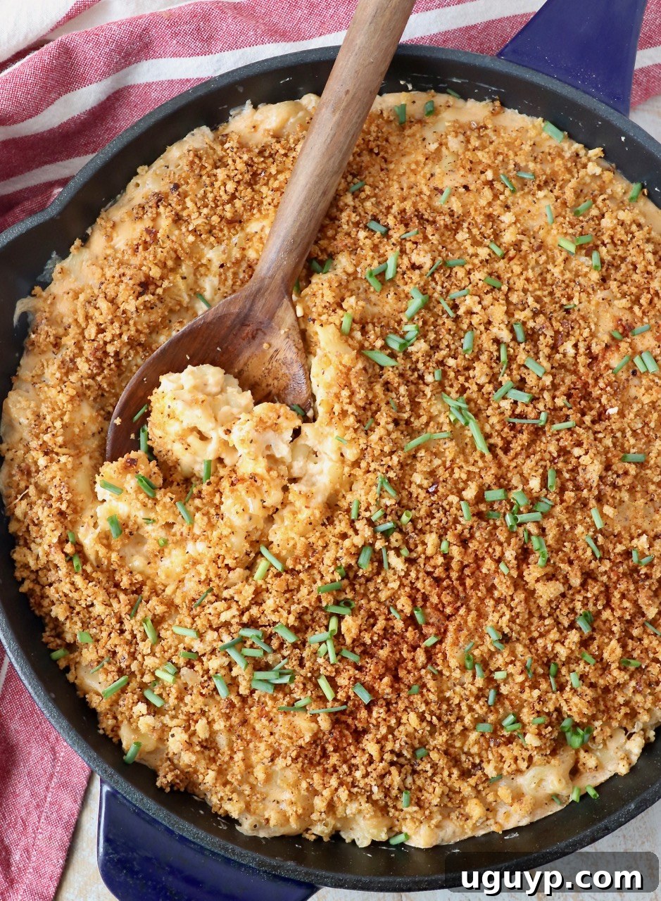 A large skillet of smoked mac and cheese with a wooden serving spoon, ready to be enjoyed.
