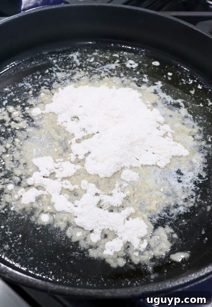 Melted butter combined with all-purpose flour, forming a smooth roux in a cast iron skillet over medium heat.