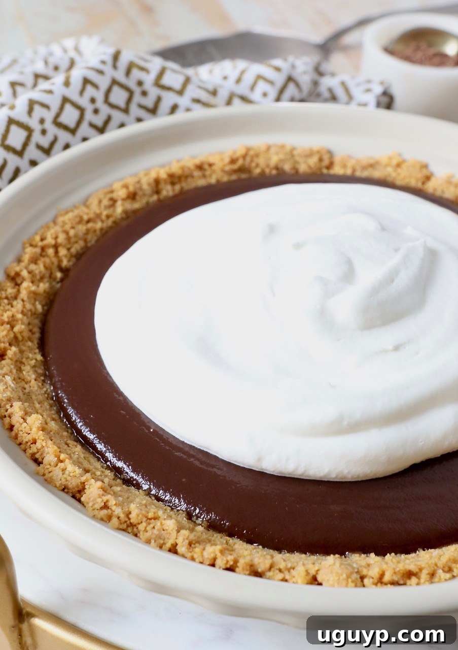 A freshly made chocolate pie in a pie plate, topped generously with homemade whipped cream, ready to be served.