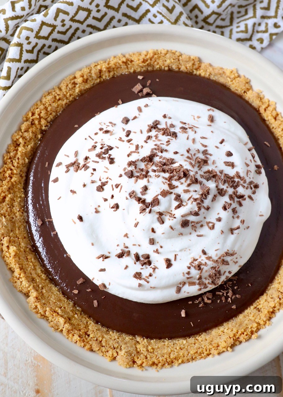 Meme's Famous Chocolate Pie with a graham cracker crust, generously topped with homemade whipped cream and delicate chocolate shavings.