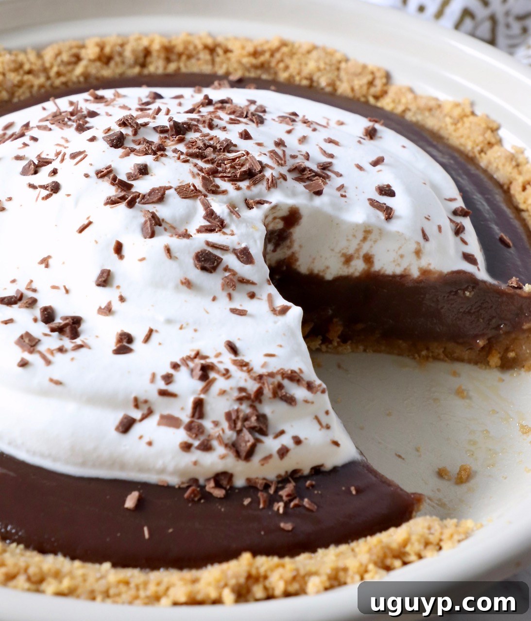 A beautiful chocolate pie topped with whipped cream, with a single slice removed, revealing the perfect texture of the filling and crust.