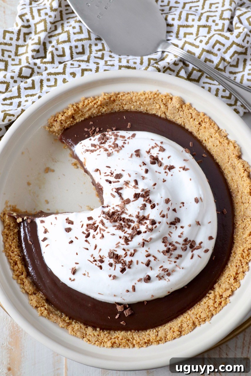 A stunning no-bake chocolate pie with a graham cracker crust, featuring a removed slice to show its perfect layers, ready to be enjoyed.