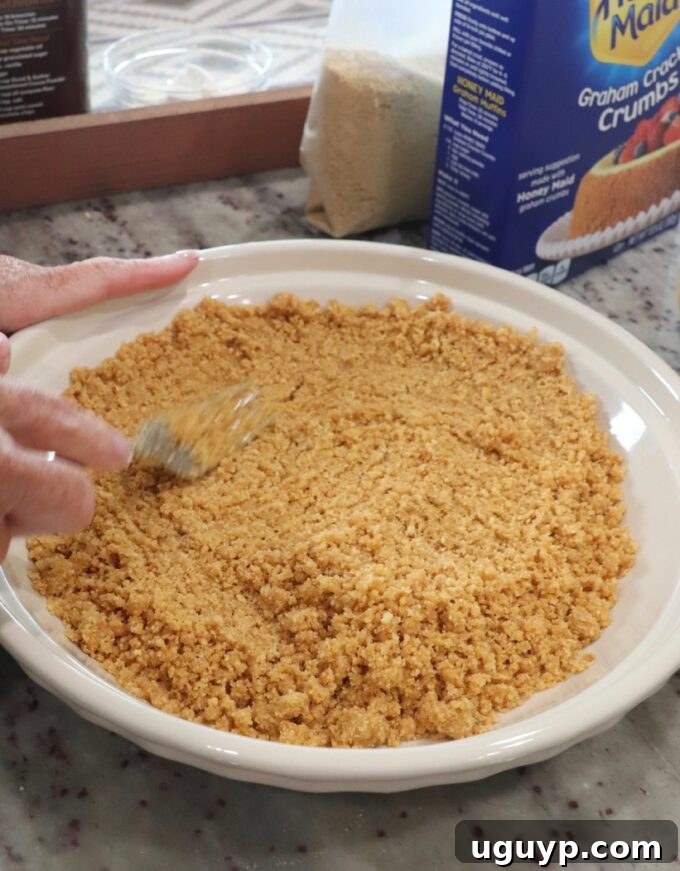 Graham cracker crumbs, sugar, and melted butter being combined in a pie plate to form the crust.