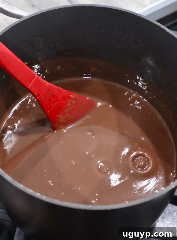 The chocolate pie filling in the saucepan, now thick and creamy, ready to be removed from the heat.