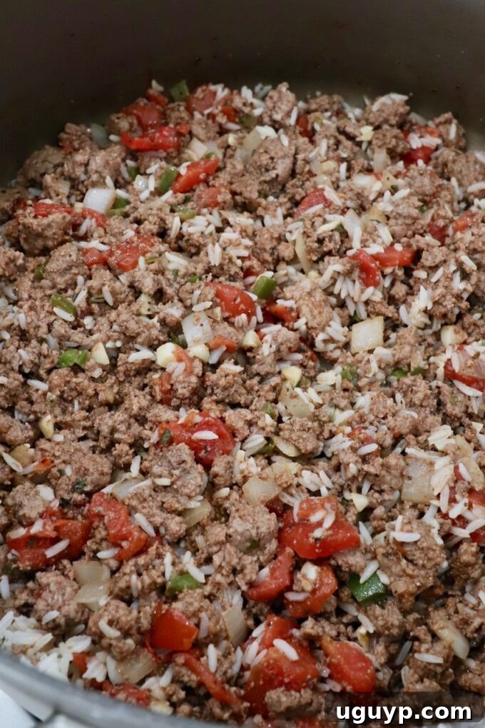 The savory ground beef filling, now mixed with cooked white rice, ready to be scooped into bell peppers.