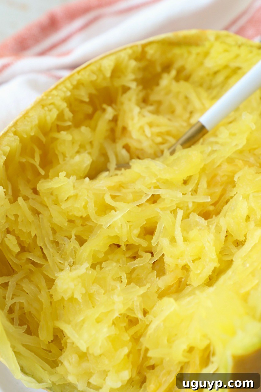 Cooked spaghetti squash strands on a plate, ready to be eaten with a fork.