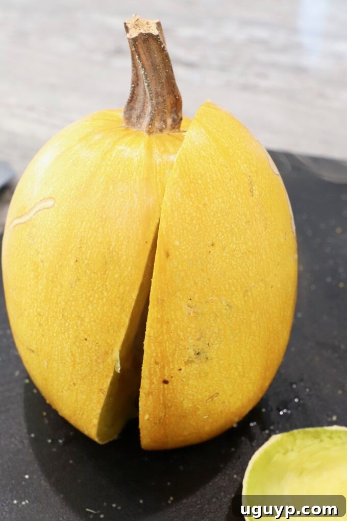 A microwaved spaghetti squash, now soft enough to stand upright on a cutting board, ready to be cut.
