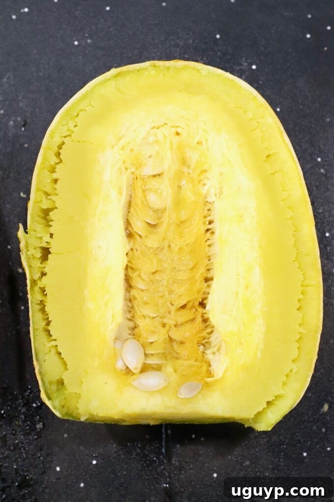 A microwaved spaghetti squash cut in half on a cutting board, revealing its cooked interior.