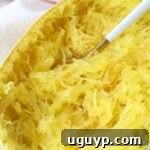 Cooked spaghetti squash on a plate with a fork, ready to serve.