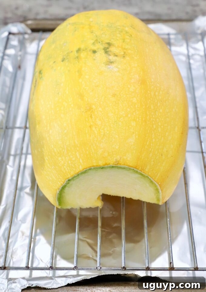 Seasoned spaghetti squash halves placed cut-side down on a wire rack over a foil-lined baking sheet.