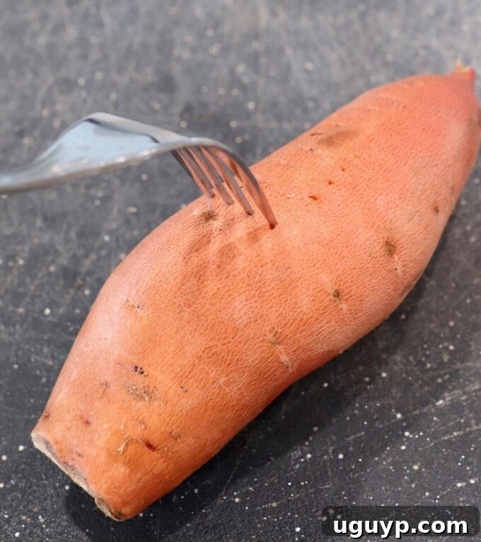Fork piercing a sweet potato on a cutting board, a crucial preparation step
