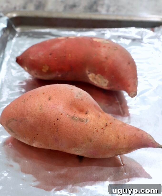 Sweet potatoes arranged on a foil-lined baking sheet, ready for the oven