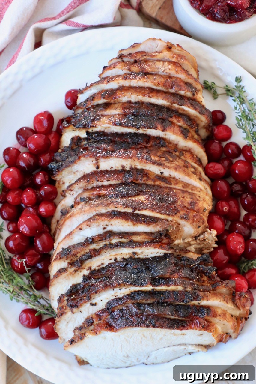 Sliced cranberry glazed turkey breast with fresh cranberries and thyme garnish