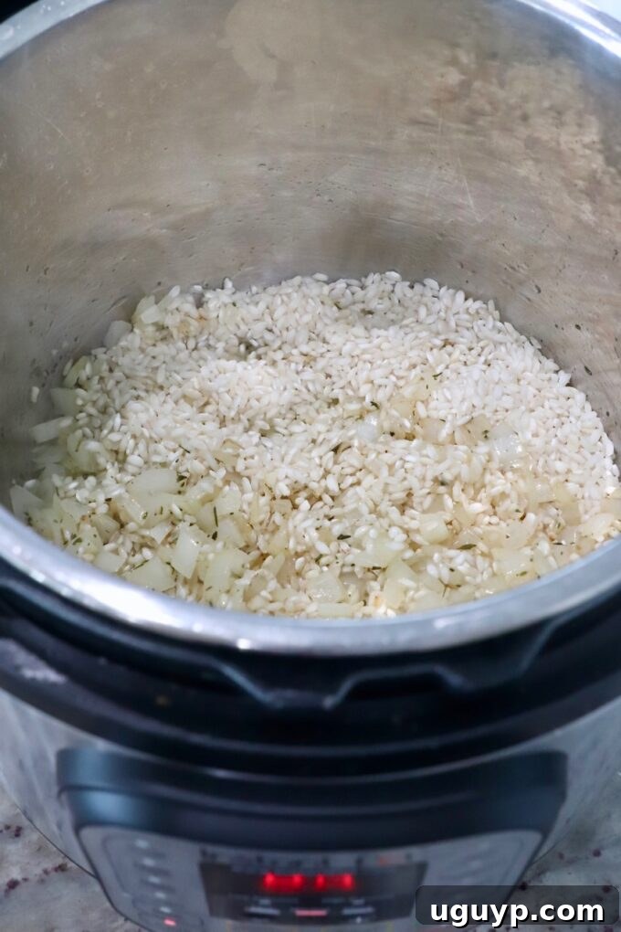 Arborio rice being toasted with cooked onions and garlic in the Instant Pot.