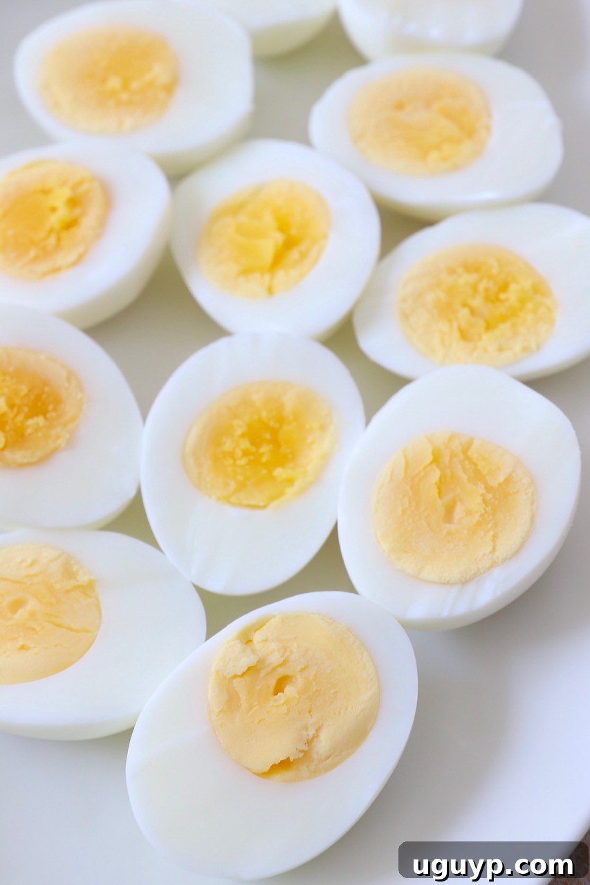 Perfectly sliced hard boiled eggs with creamy yellow yolks on a clean white plate, ready for serving or meal prep.