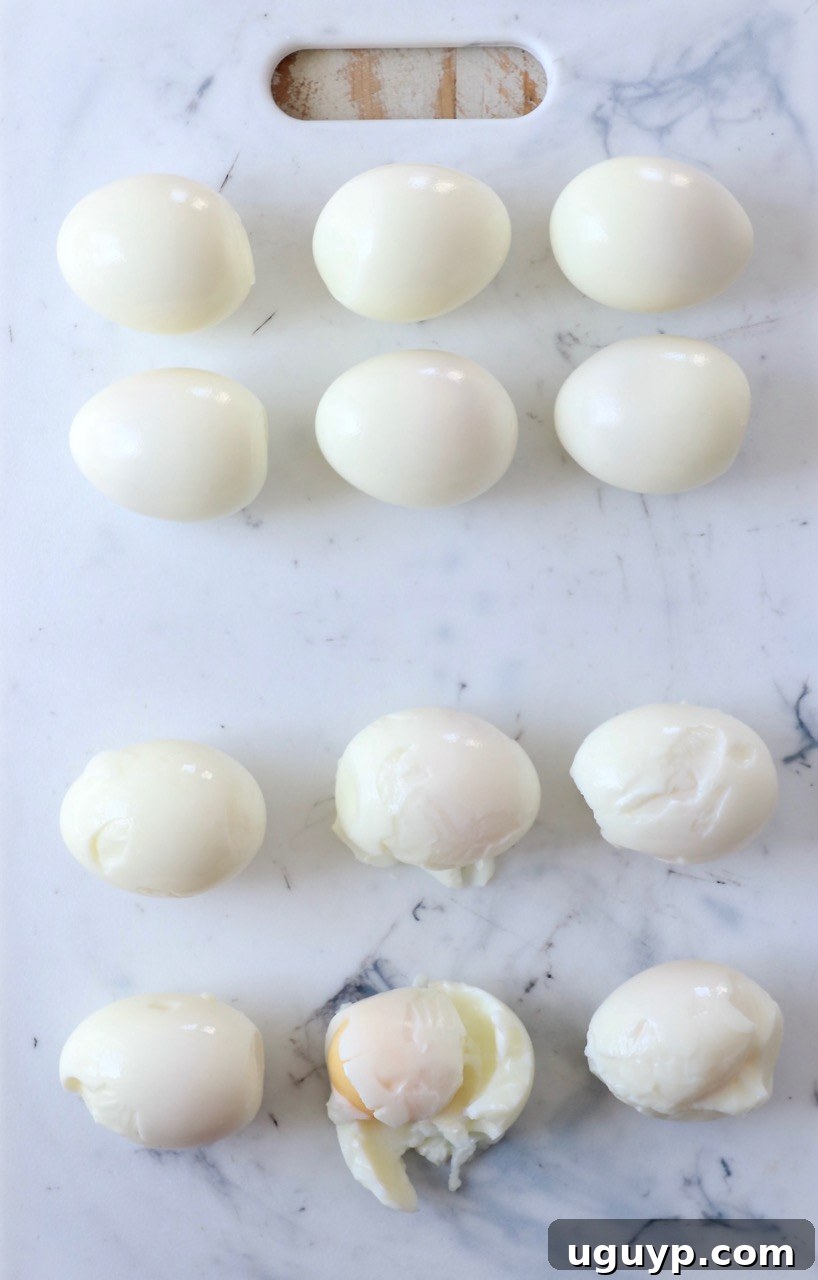 A row of perfectly peeled hard boiled eggs resting on a wooden cutting board, showcasing their smooth white exterior.