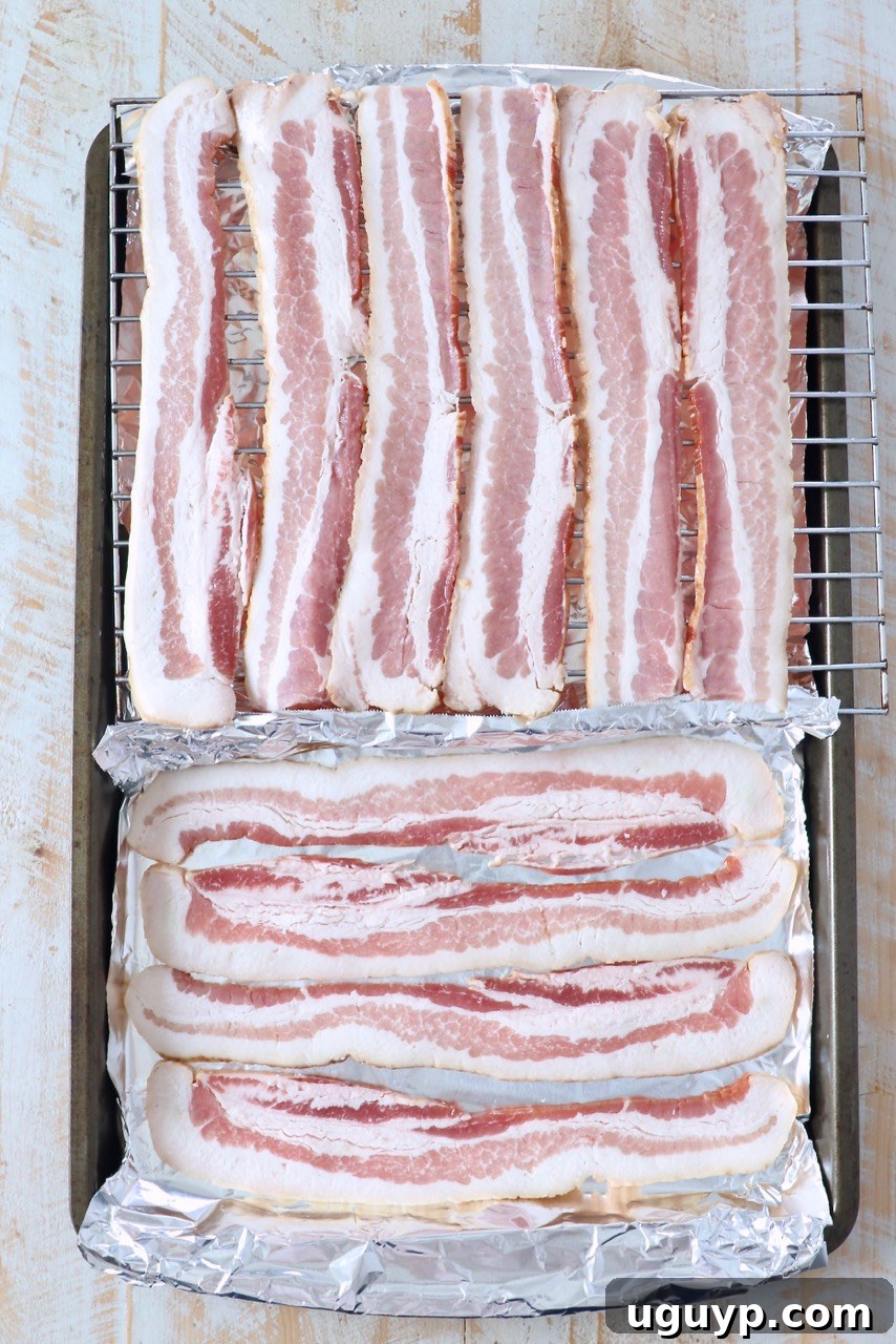 Uncooked bacon slices laid out neatly in a single layer on a baking sheet, ready for the oven, showcasing the simplicity of preparation.