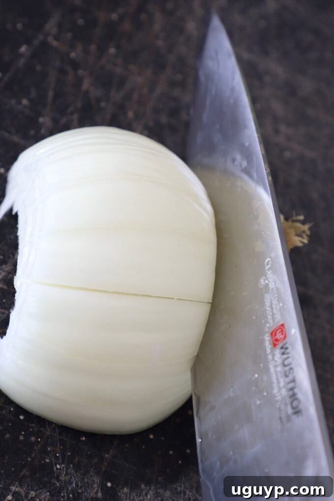 knife cutting an onion on cutting board