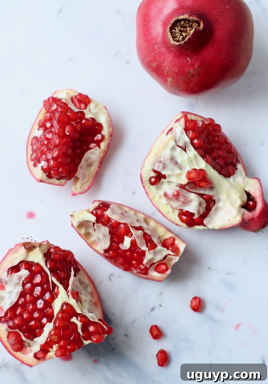 Pomegranate cut into pieces on a white cutting board, showcasing its vibrant arils.