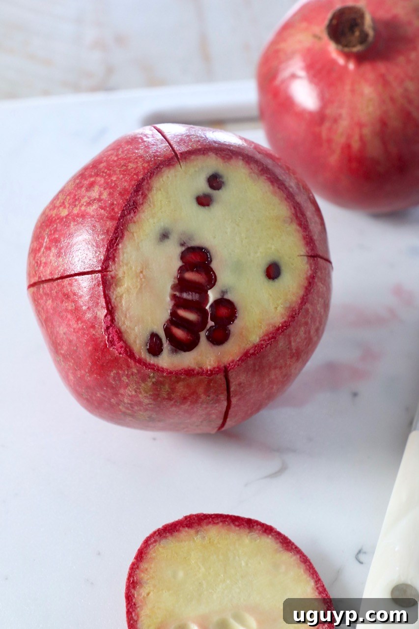 Fresh pomegranate cut on a cutting board, illustrating its internal structure.