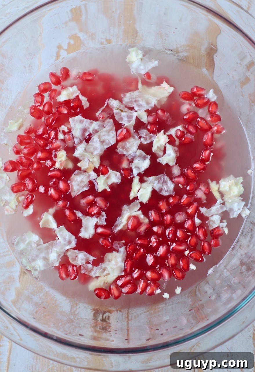 Pomegranate seeds (arils) in a glass bowl of water.
